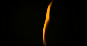 Una llama clara arde sobre un fondo oscuro.