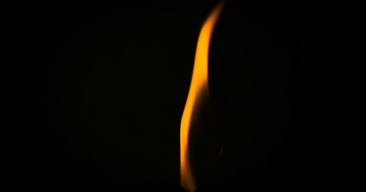 Una llama clara arde sobre un fondo oscuro.